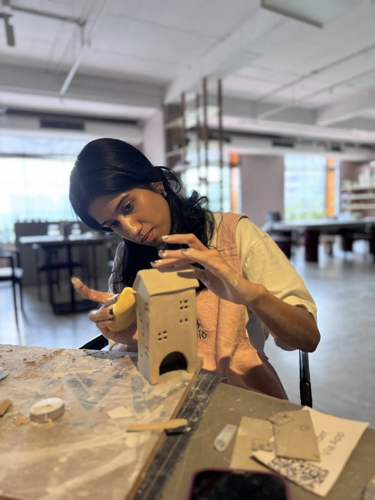 Aishwarya sponging the walls of a little slab-built clay house