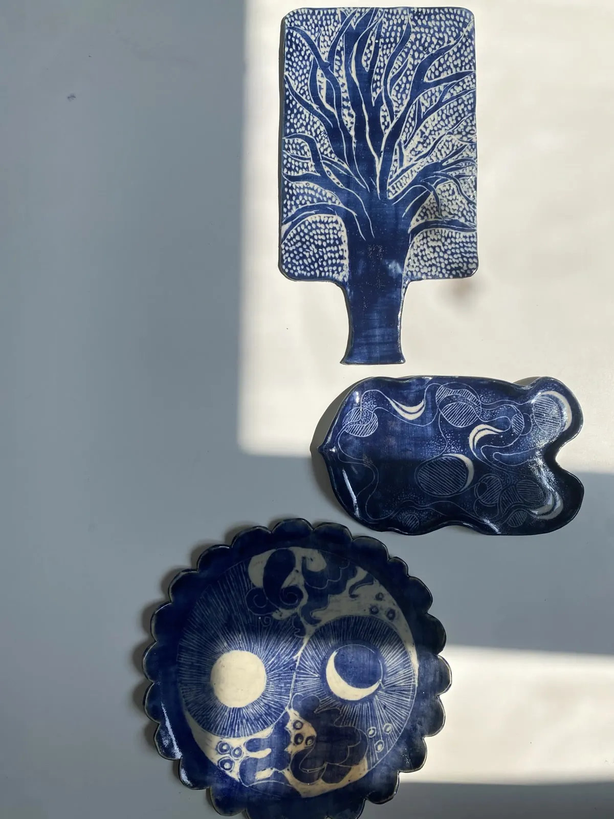 Three cobalt-blue dishes — a tree board, a wavy tray and a scalloped sun-and-moon plate
